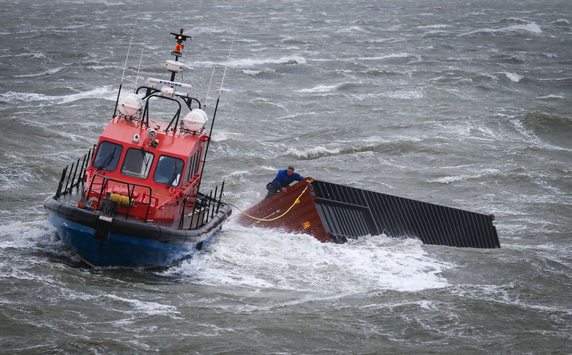 Reddingboot bij een gedeeltelijk ondergedompelde container op zee