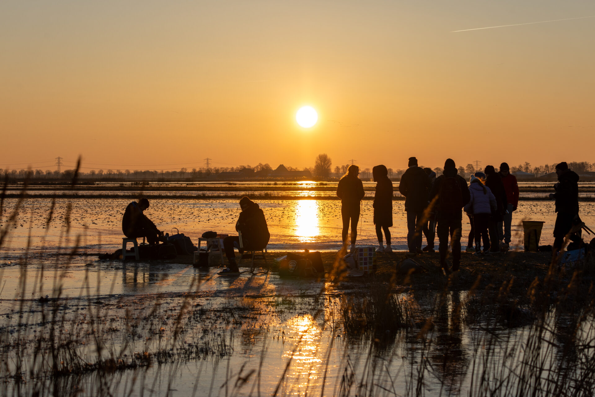 Schaatsers op natuurijs bij zonsondergang