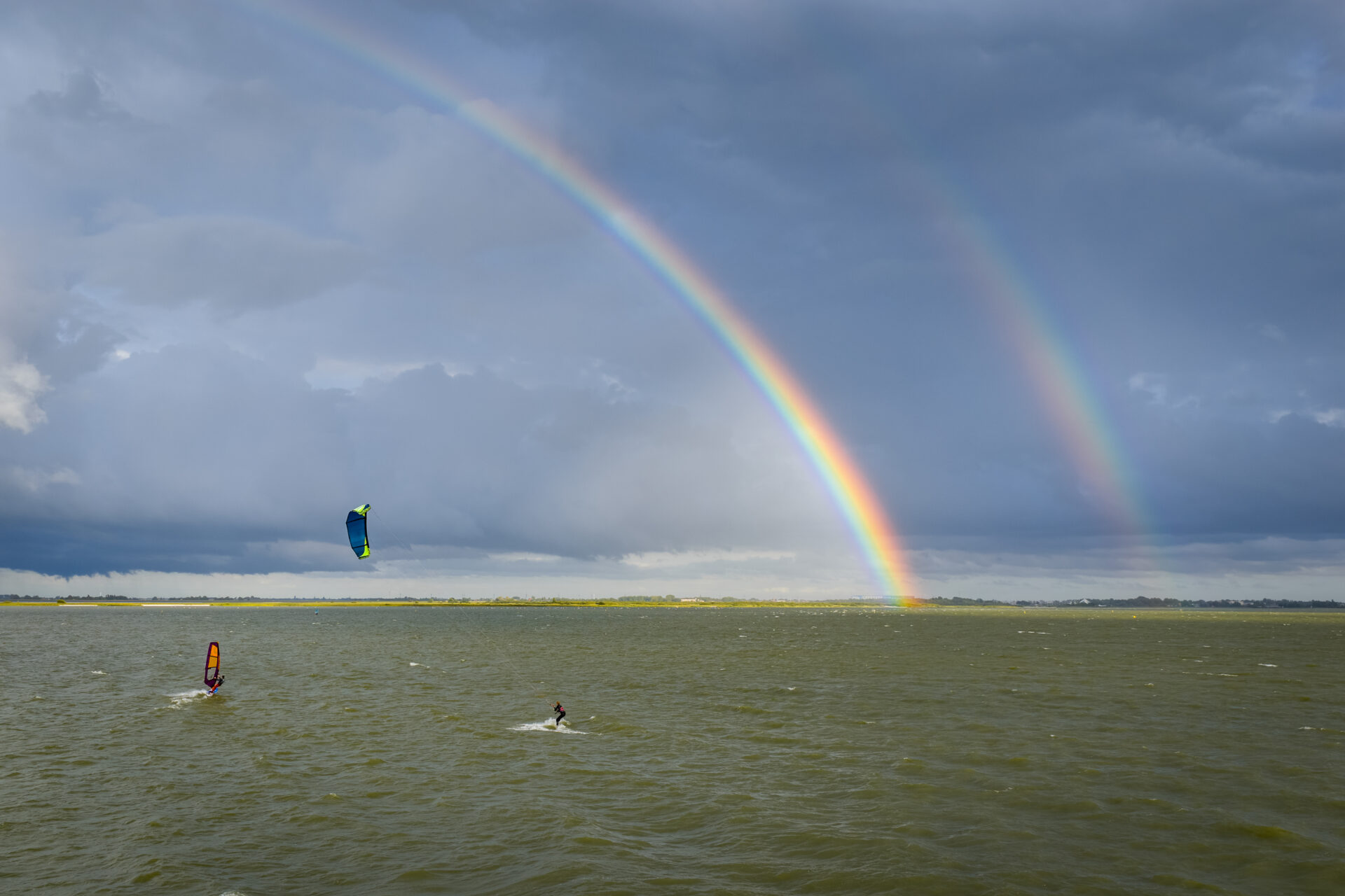Kitesurfers onder een dubbele regenboog